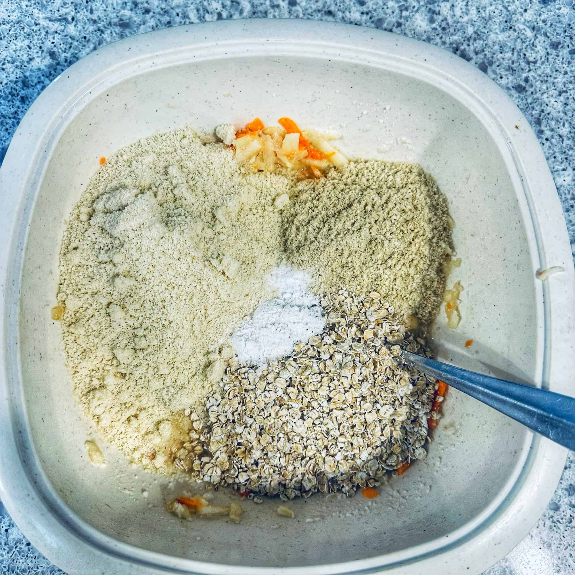 Image of dry ingredients being added to wet ingredients in a white bowl for step 3 for ABC muffins.
