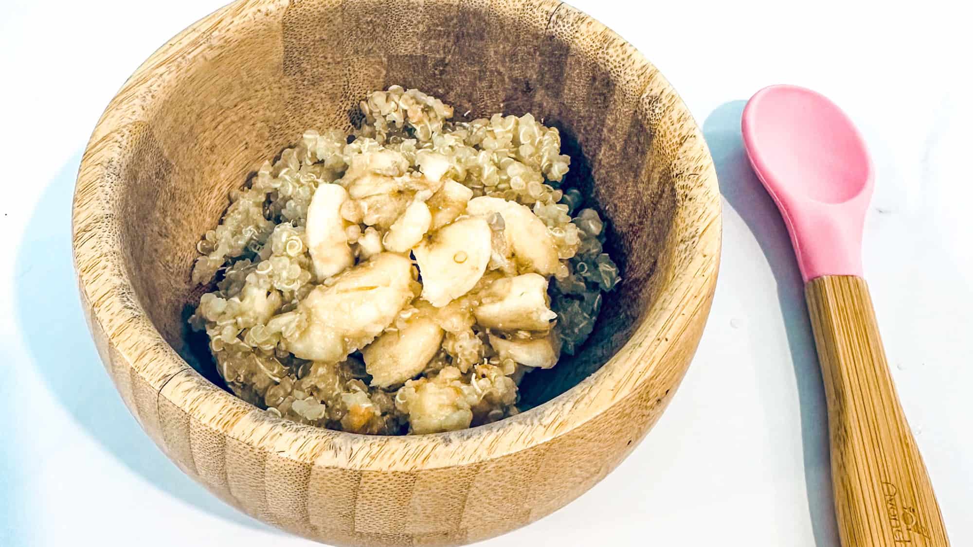 Step 3 of quinoa baby cereal with banana on top served in a bowl.