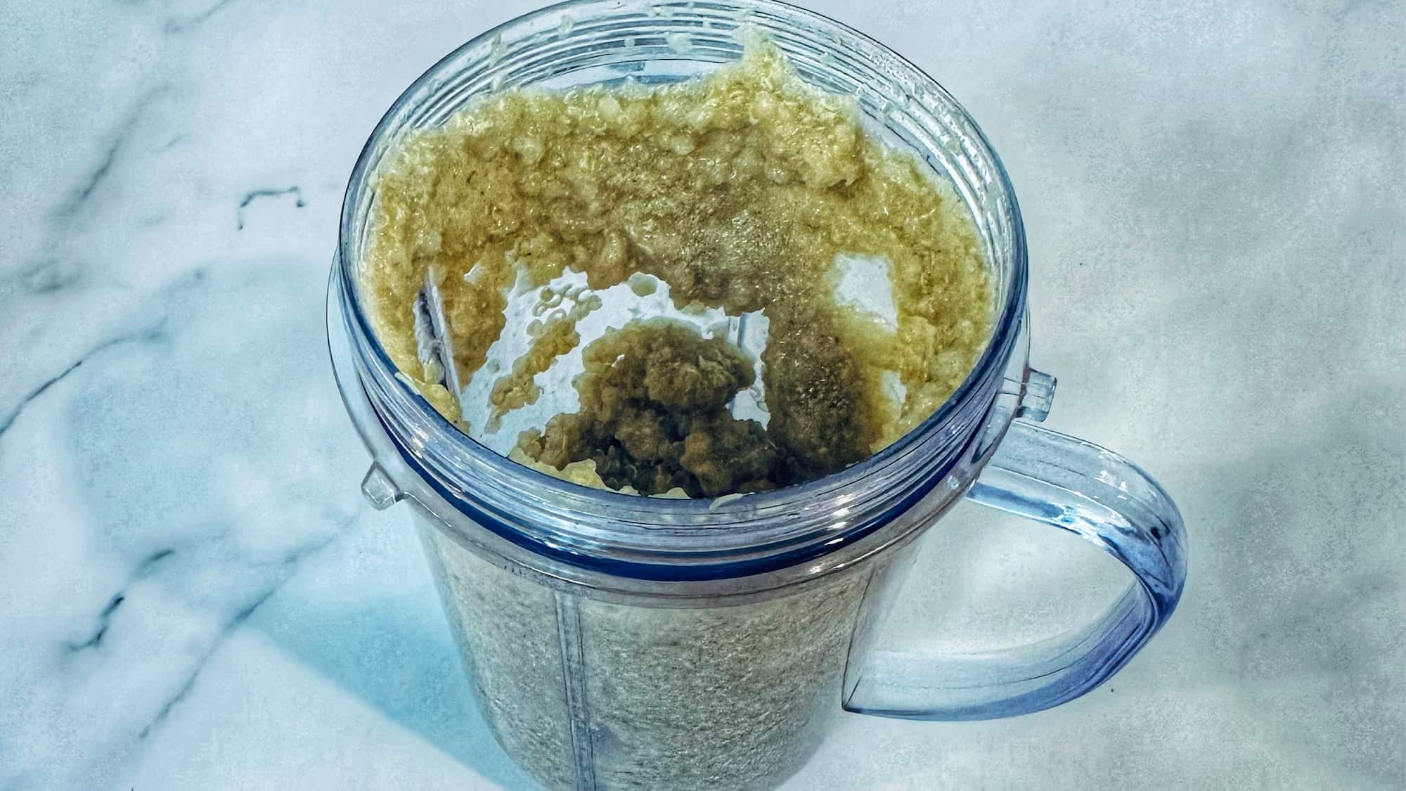 Step 2 of baby quinoa cereal. Bending quinoa with liquid of choice in a blender cup.