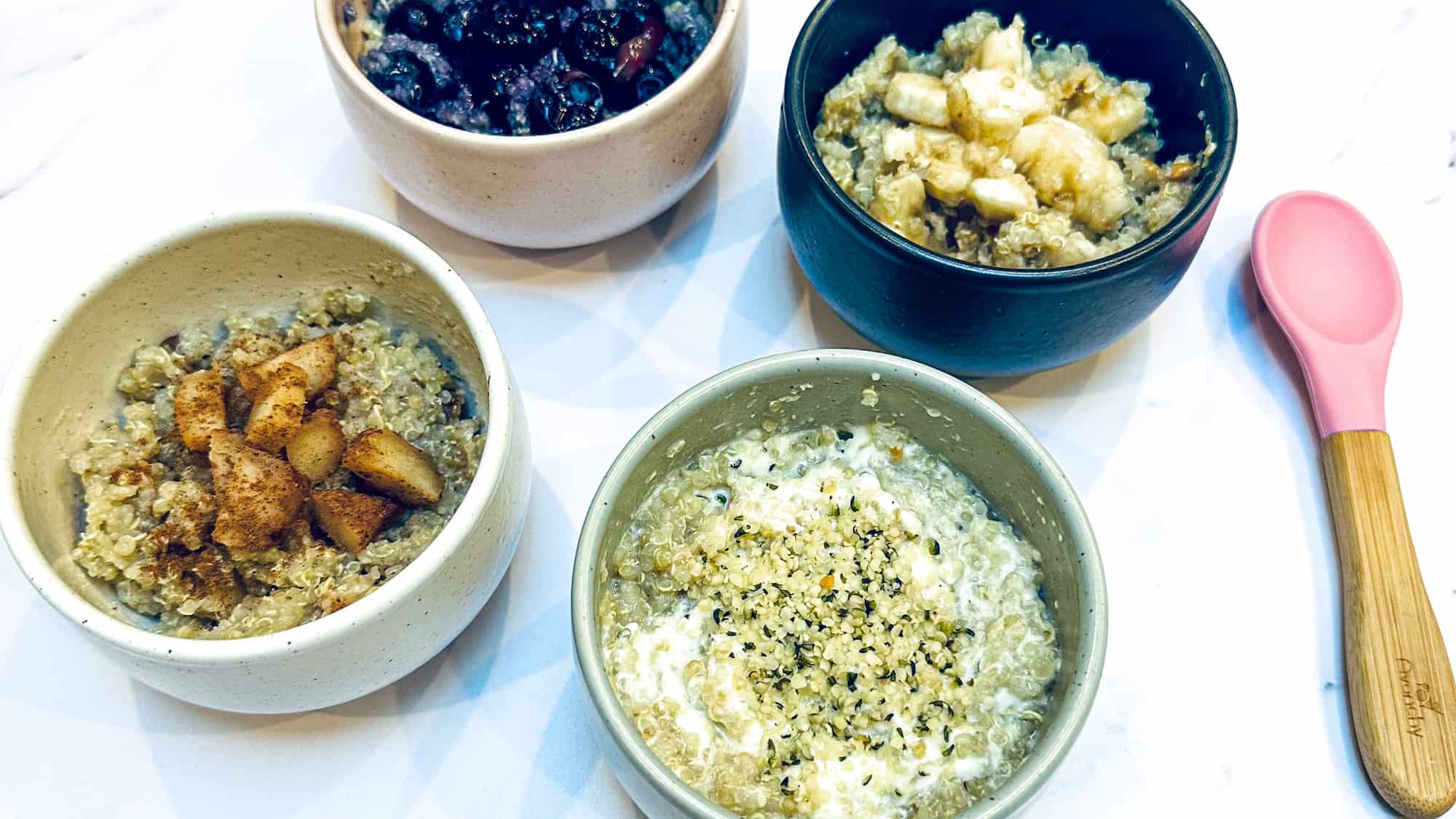 Image of Baby Quinoa Cereal in 4 different bowls with various toppings including cinnamon apples, yogurt and hemp seeds, banana and peanut butter and blueberries.