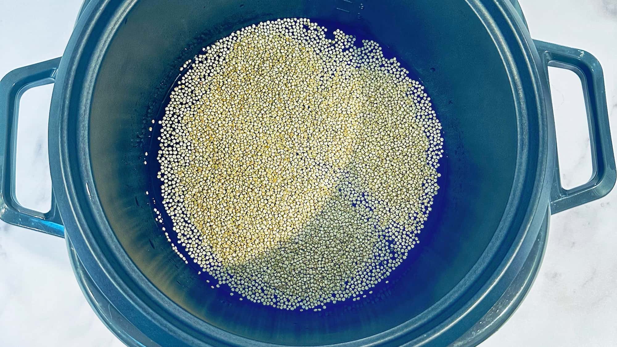 Step one of baby quinoa cereal, adding quinoa into a rice cooker with water.