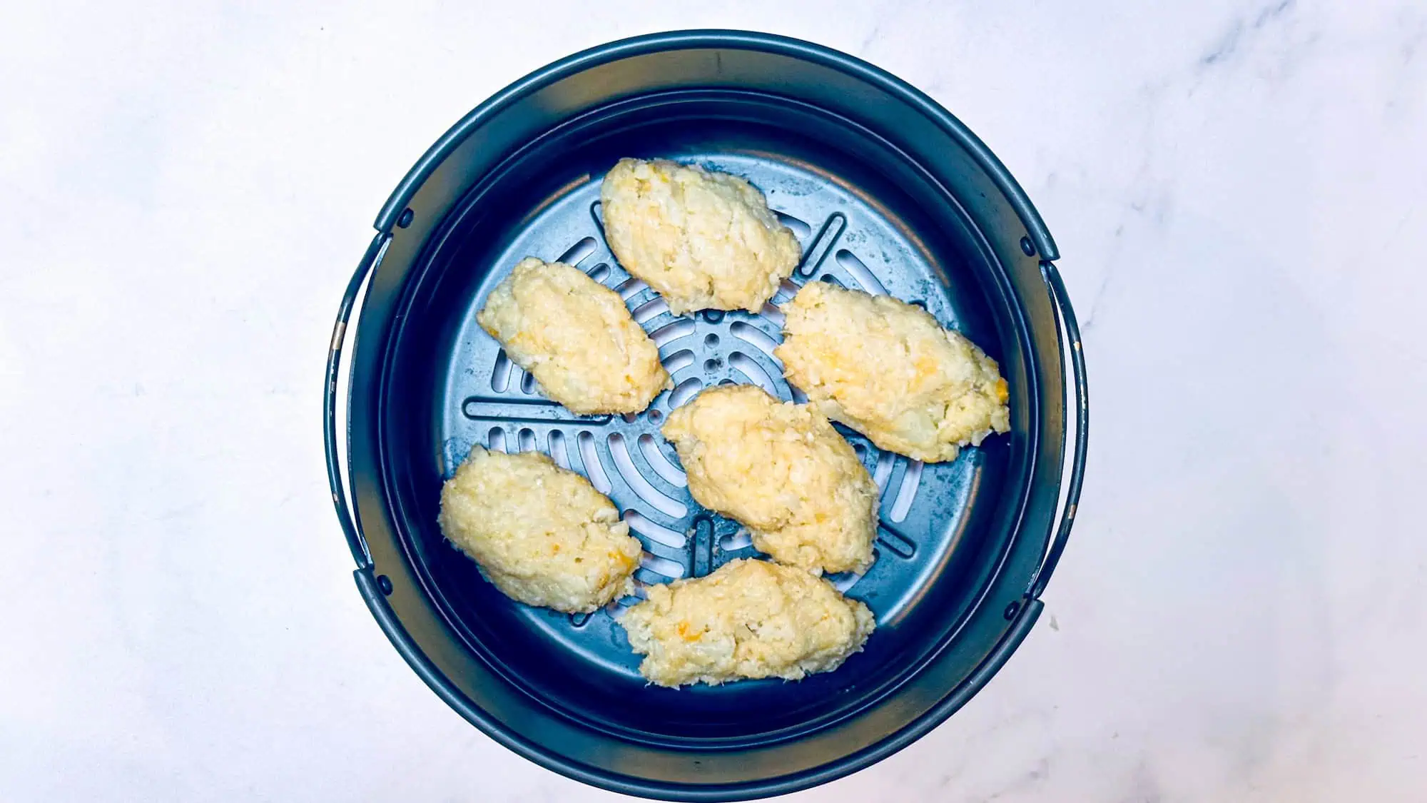 Step 4 for cauliflower tater tots - putting into air fryer basket to cook.