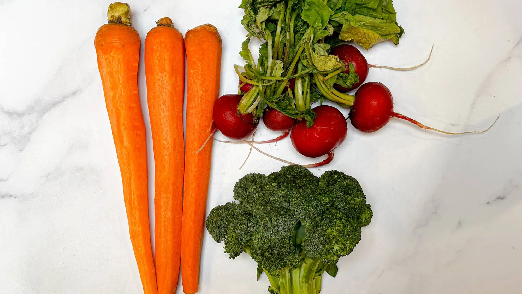 Ingredients for roasted vegetables for toddlers including carrots, broccoli and radishes.