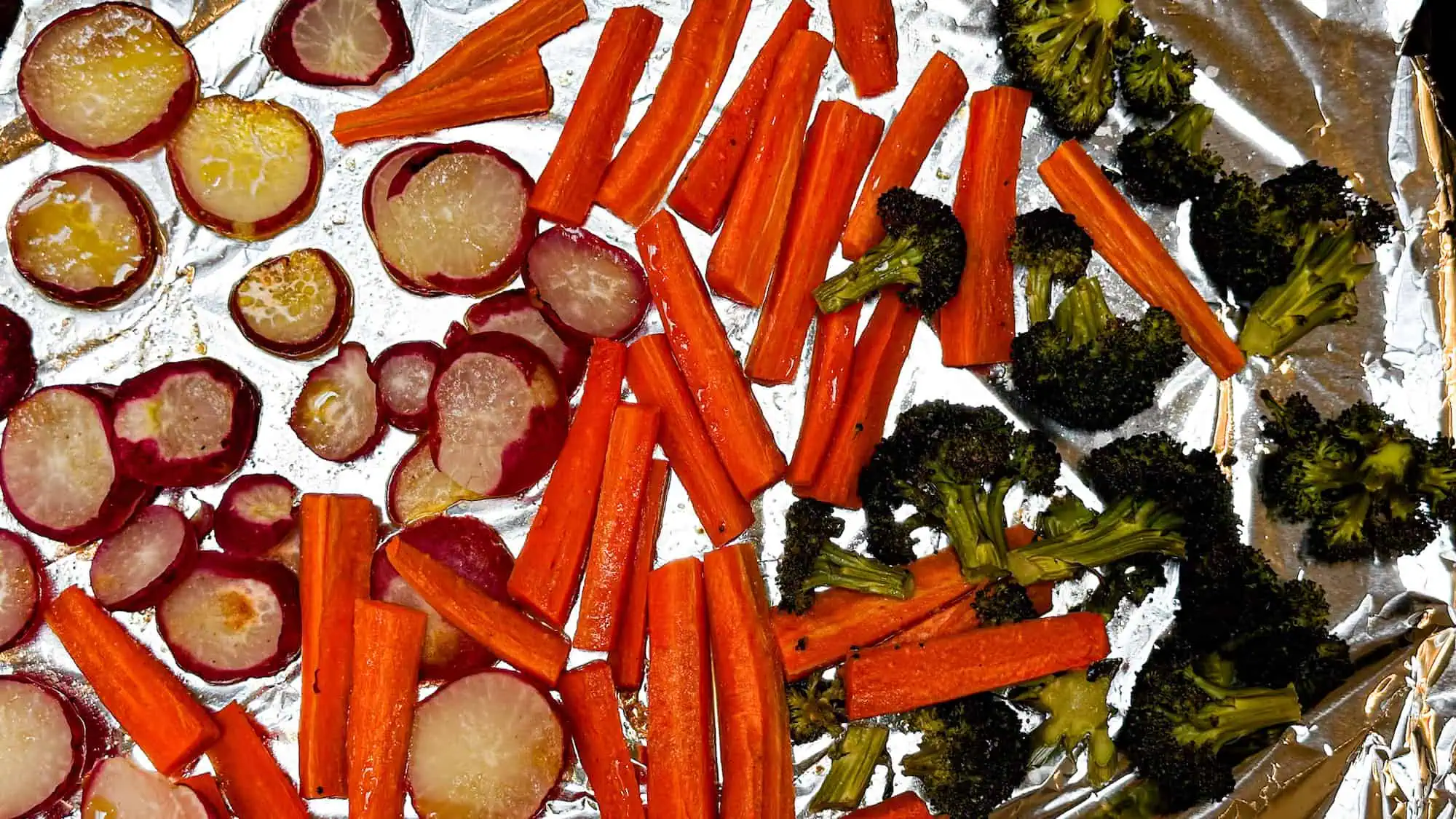 Vegetables after being roasted on a pan lined with tinfoil.