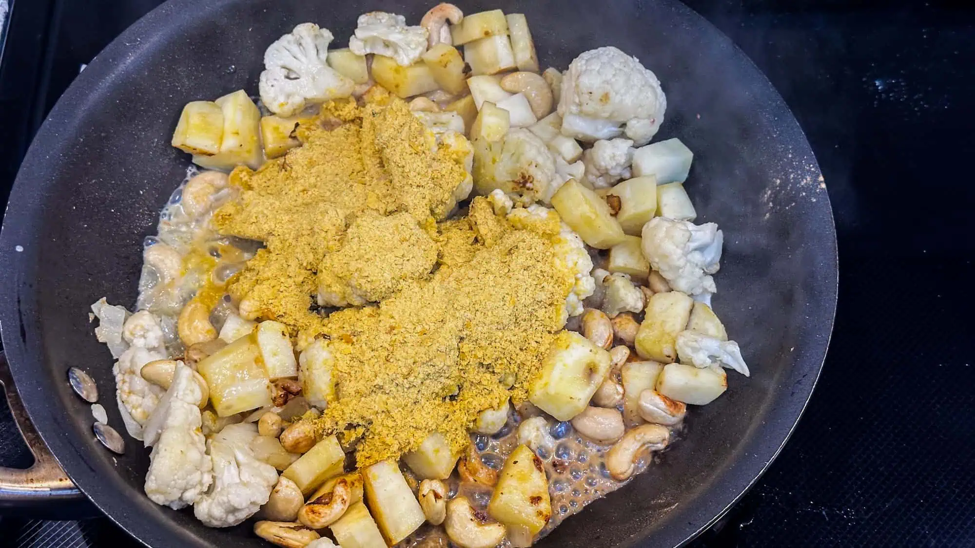 Step 3 for dairy-free mac and cheese. Add nutritional yeast and almond milk to frying pan.