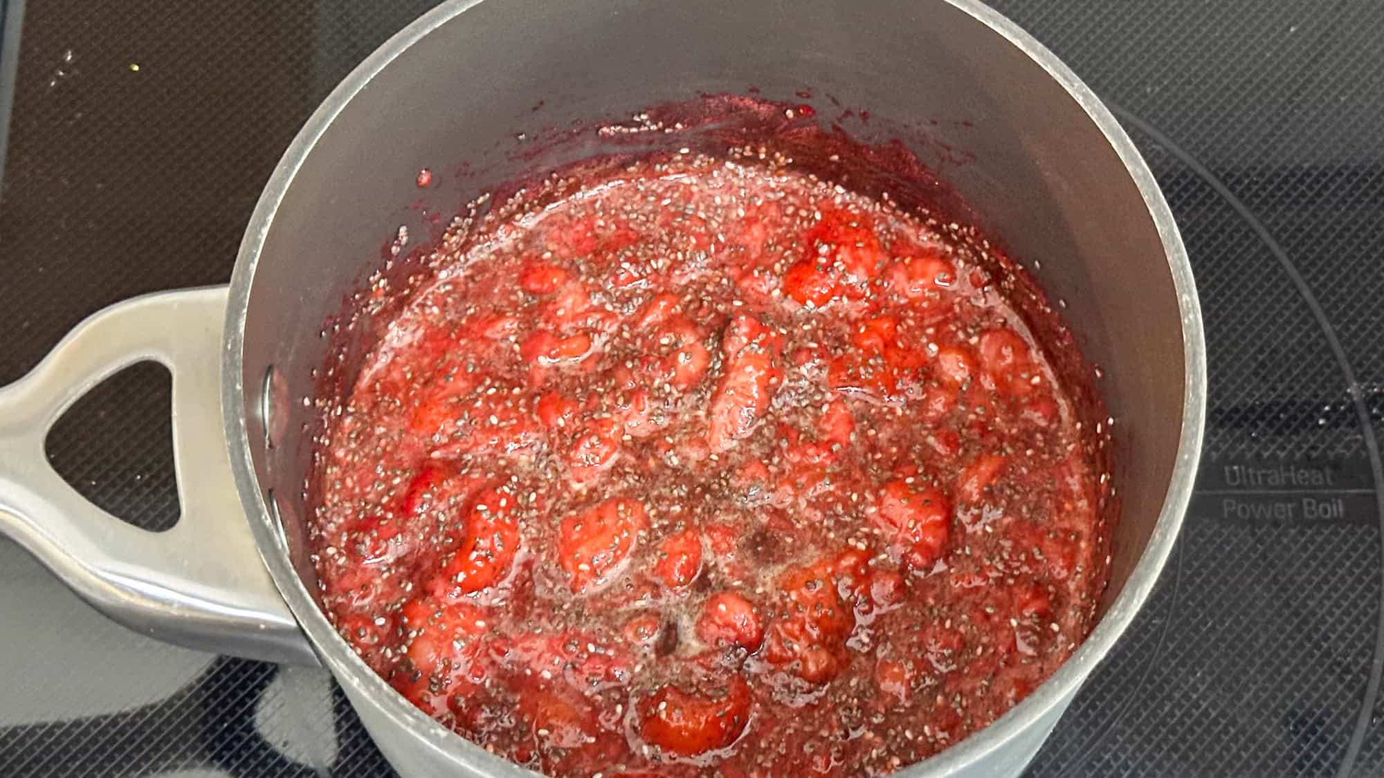 Step 2 of strawberry chia jam, add chia seeds, lemon and vanilla to strawberries in saucepan.