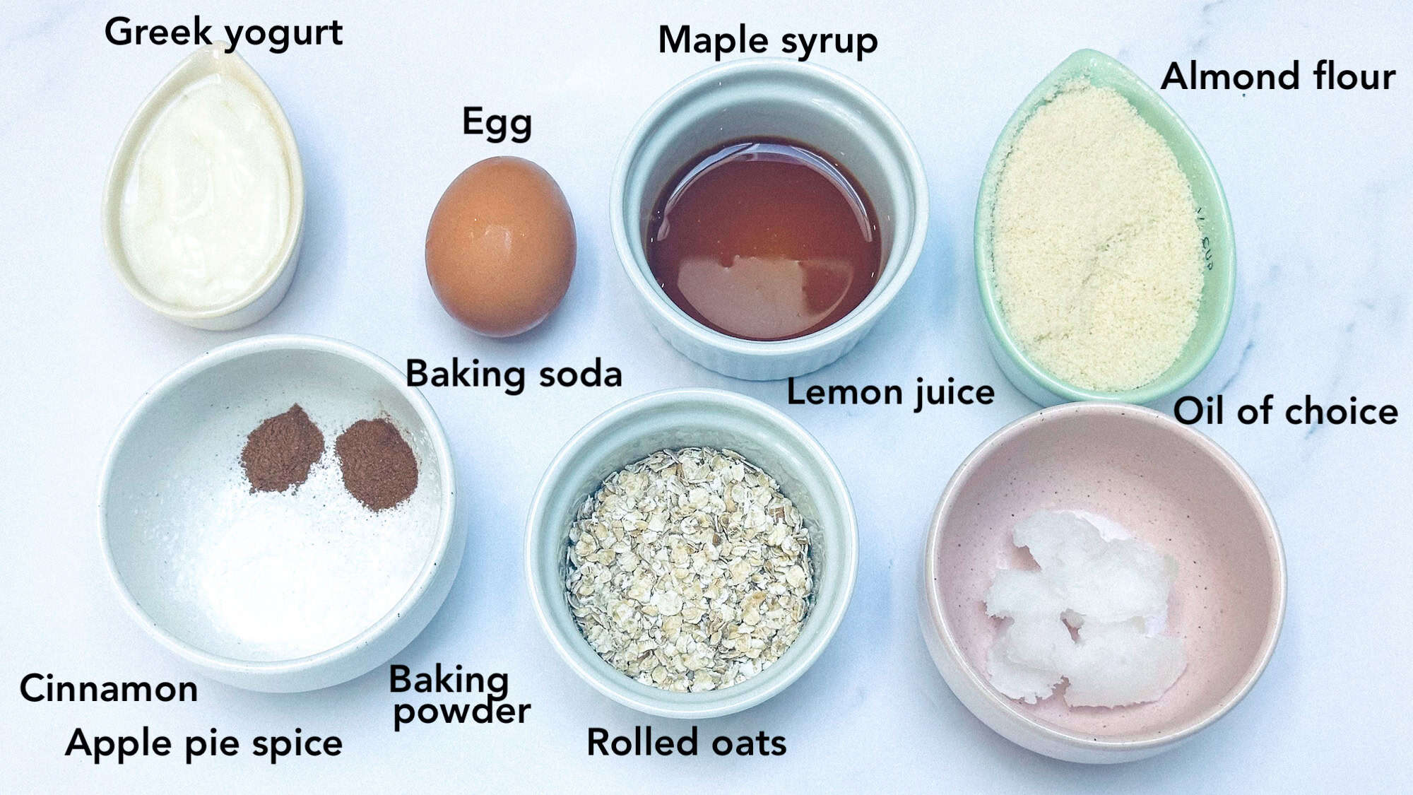 Ingredients for almond flour and oatmeal pancakes labelled and on white marble background.