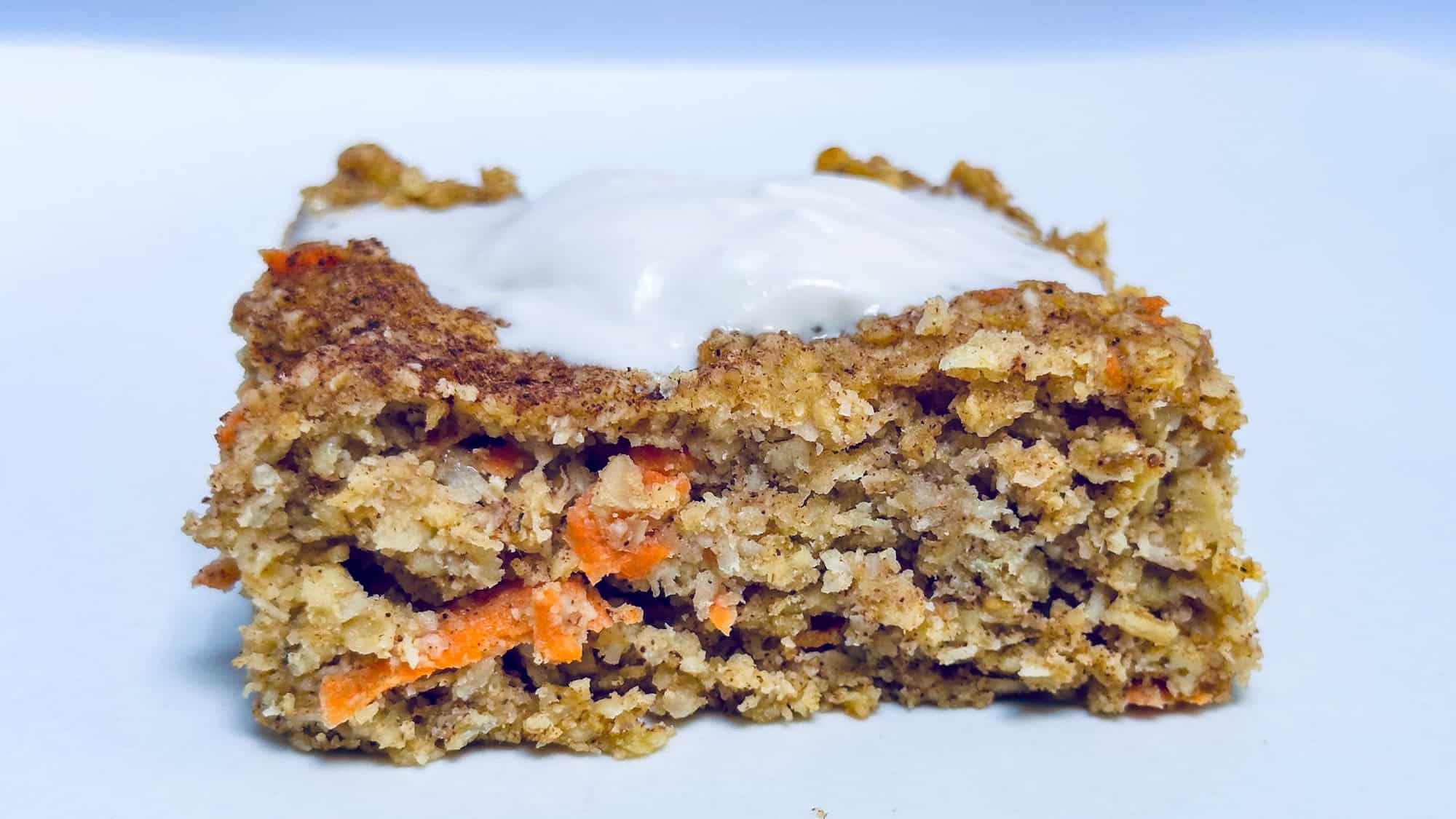 Baked Carrot Cake Oatmeal on white plate with greek yogurt on top.