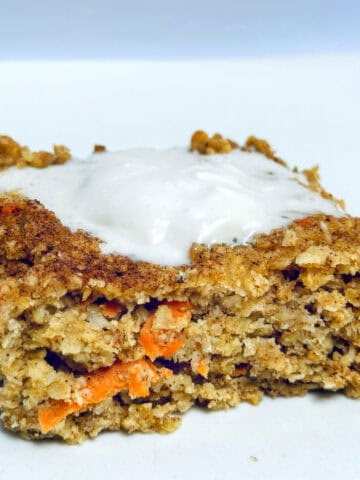 Baked carrot cake oatmeal on white plate with yogurt topping.