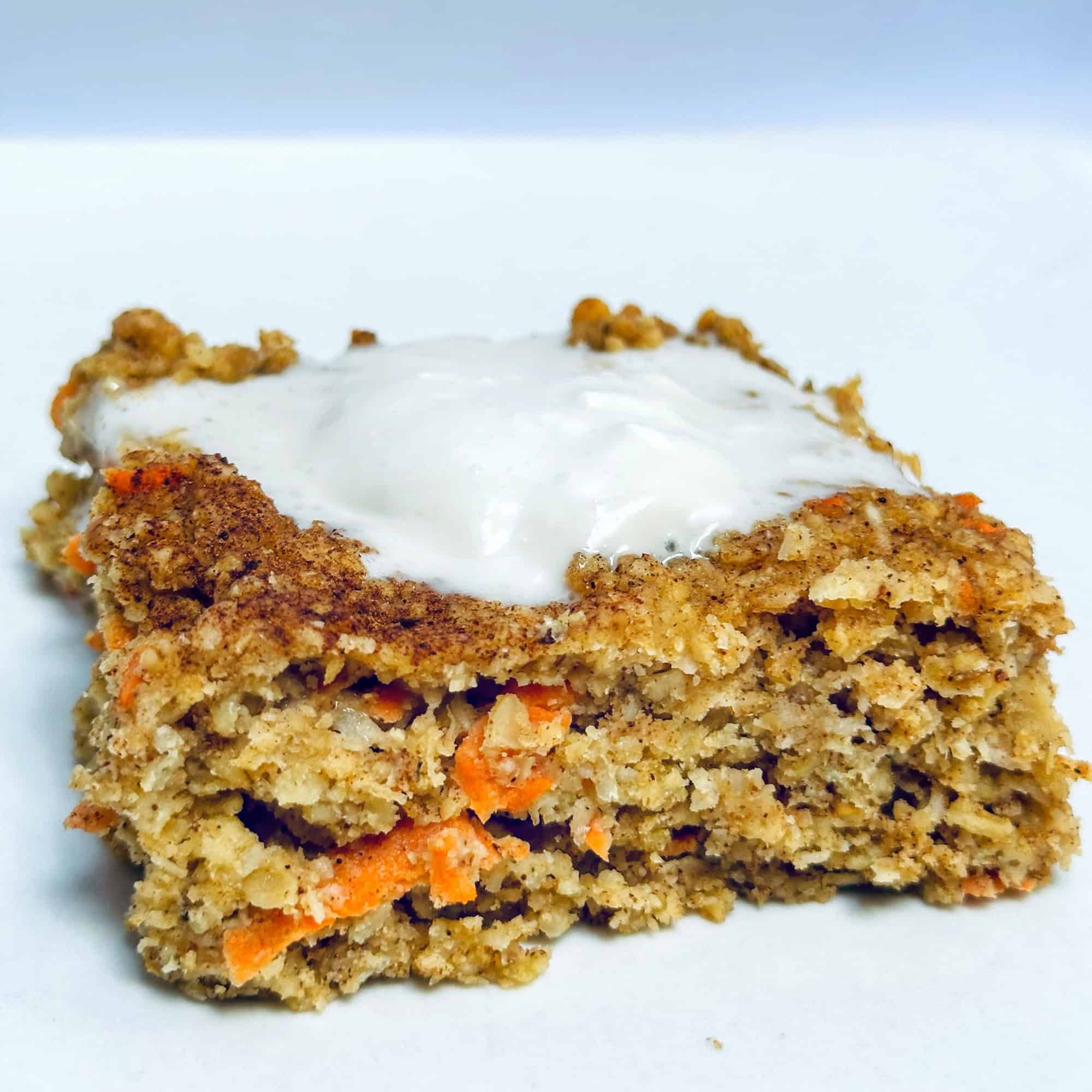 Baked carrot cake oatmeal on white plate with yogurt topping.