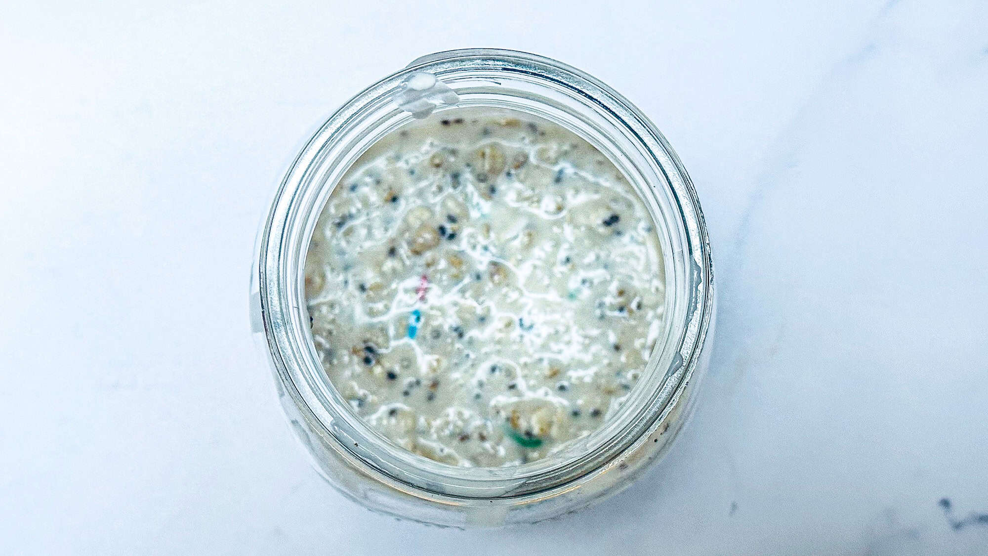 Image of ingredients for birthday cake overnight oats added to glass mason jar and mixed together.