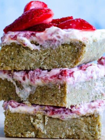 Strawberry yogurt bars stacked on top of one another with blue background and on wooden board.