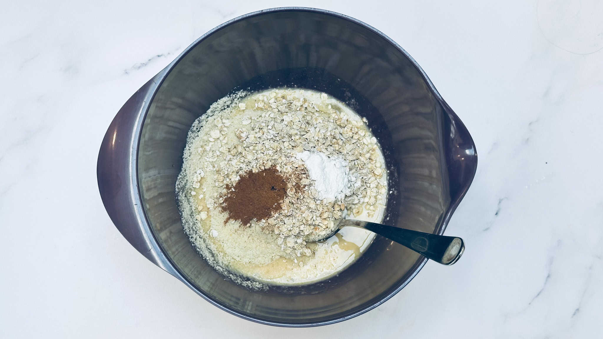 Step 1 for pancakes. All ingredients are added to a purple bowl.