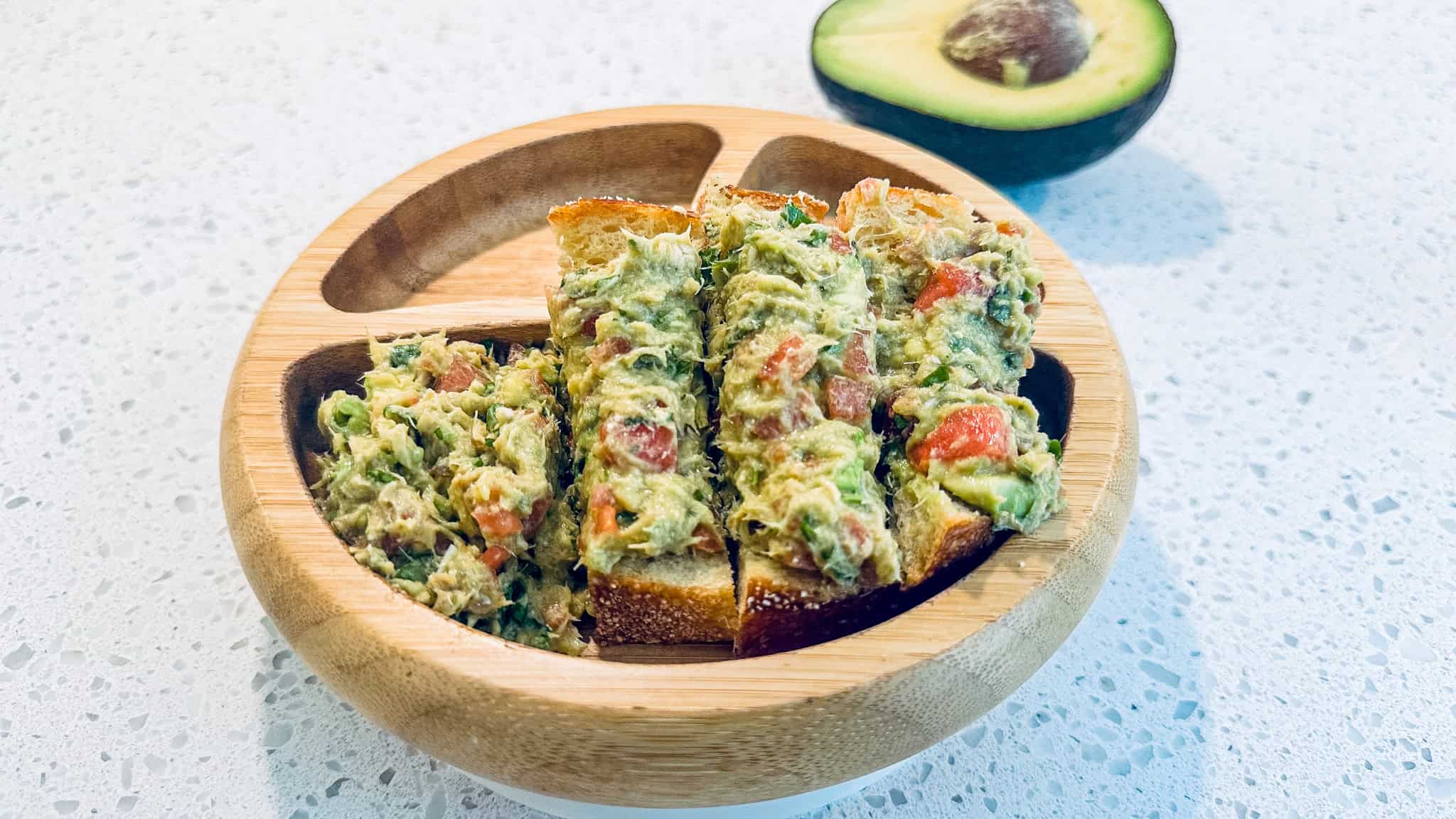 Salmon, avocado and watermelon mash in toddler wooden bowl.