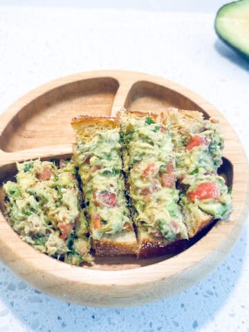 Salmon, avocado and watermelon mash in toddler wooden bowl.