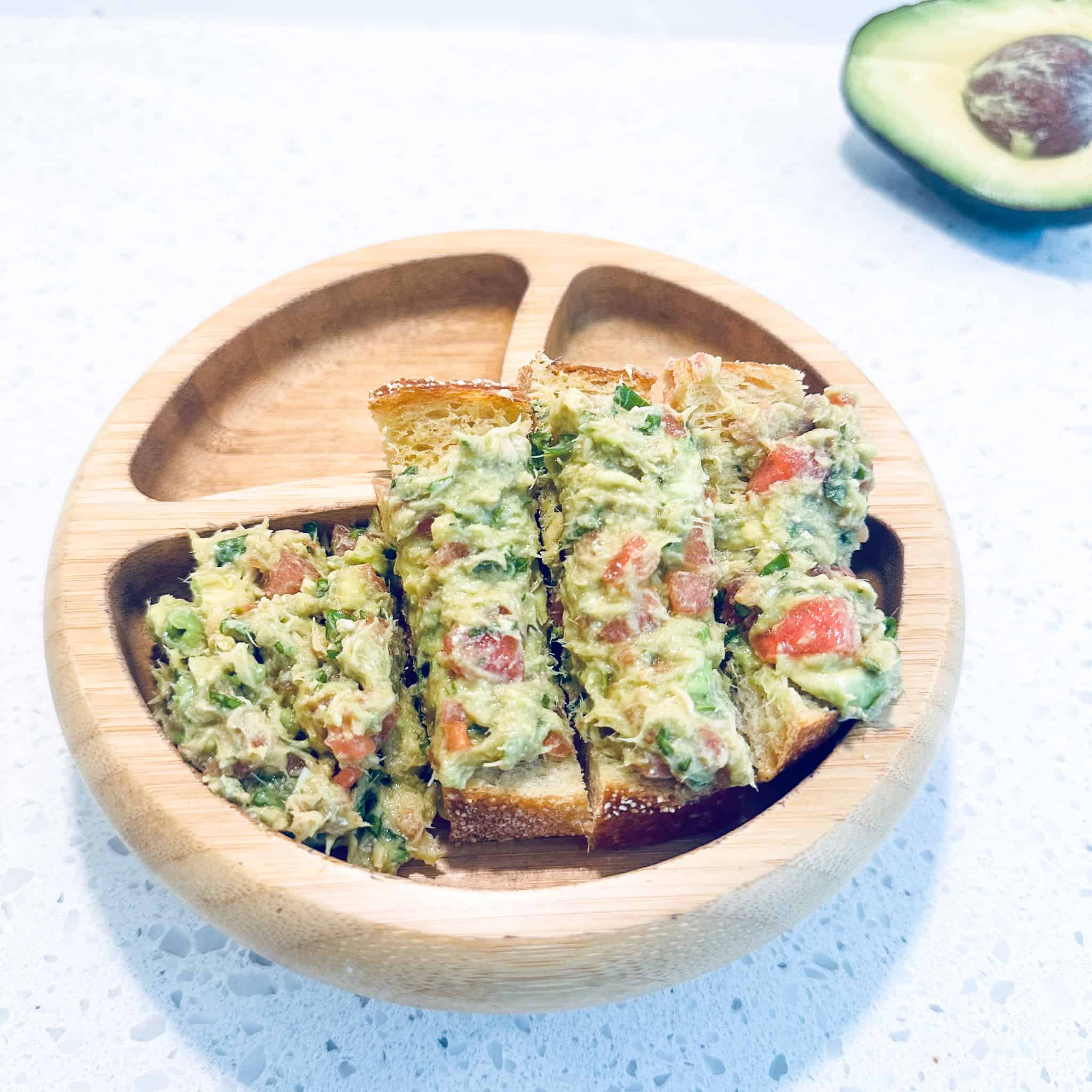 Salmon, avocado and watermelon mash in toddler wooden bowl.