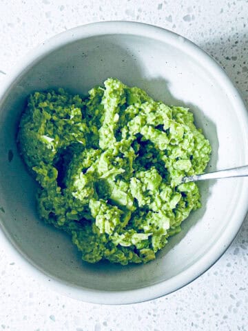 Guacamole in a white bowl with a silver spoon.