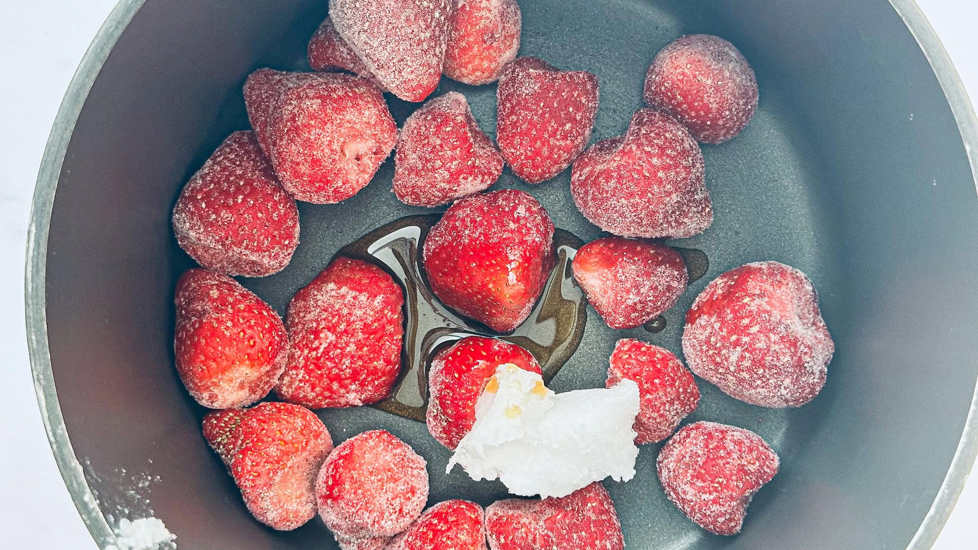 Step 1 making the strawberry chia mixture. Strawberries are added to a pot with coconut oil.