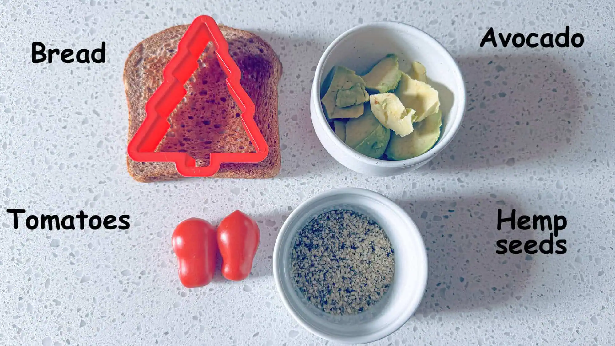 Ingredients for Avocado Toast Christmas Trees. Bread, tomatoes, avocado and hemp seeds on white marble background.