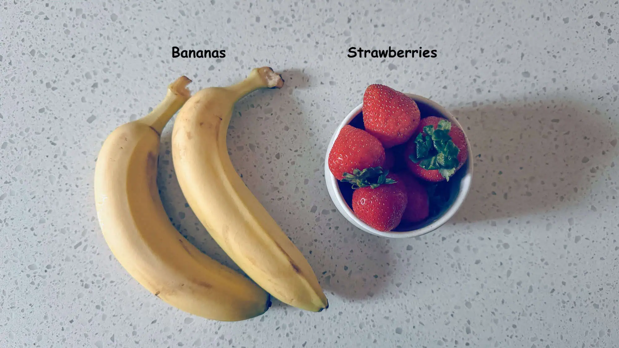 Image of bananas and strawberries for the fruit candy canes on white marble countertop.