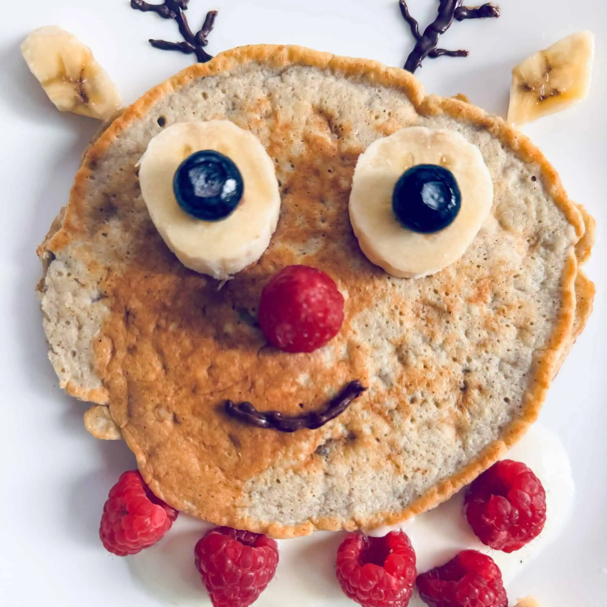 Reindeer pancake with banana and blueberry eyes and raspberry scarf.