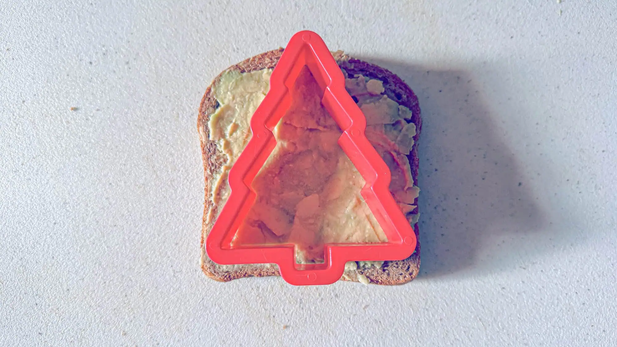 With a Christmas tree cookie cutter, cut out a tree shape from the toast.