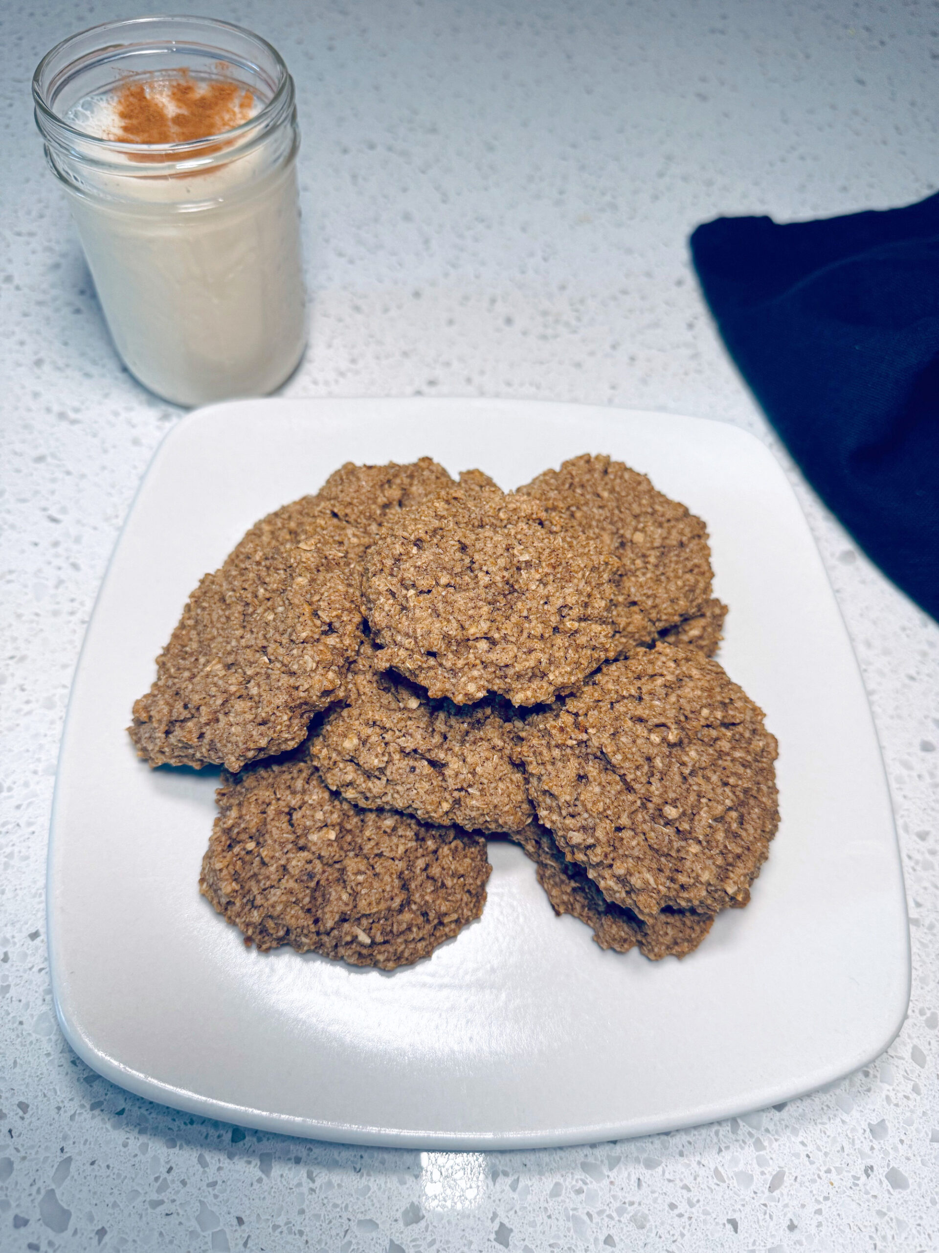 Image of vegan eggnog cookies on white plate with cup of milk.