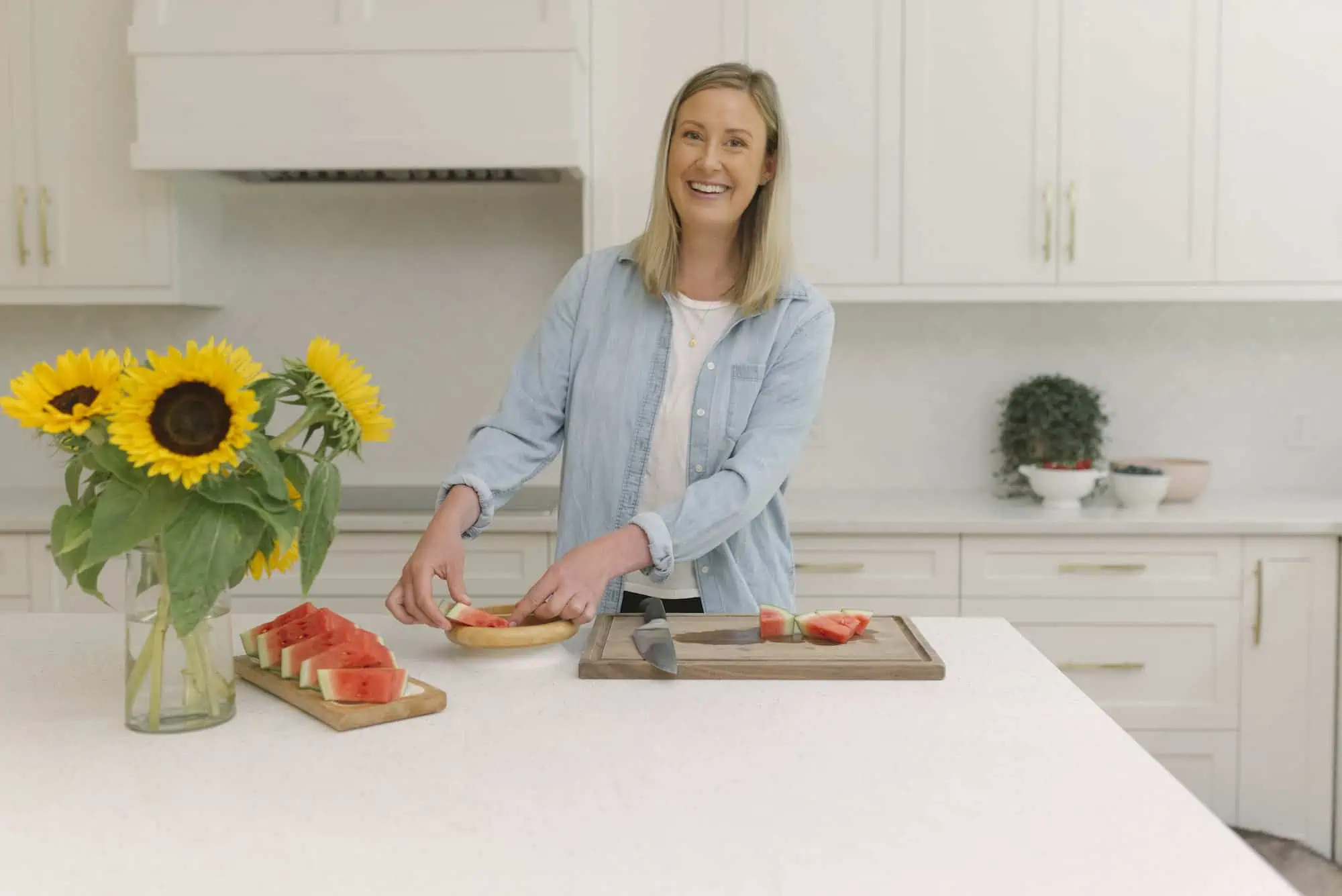 Dietitian in white and blue shirt at kitchen counter cutting watermelon.