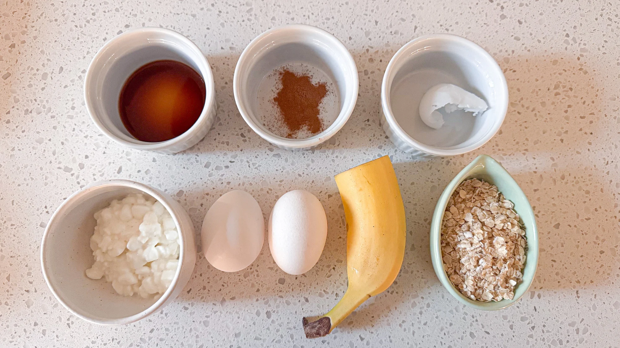 Ingredients for cottage cheese banana pancakes on a white marble counter top.