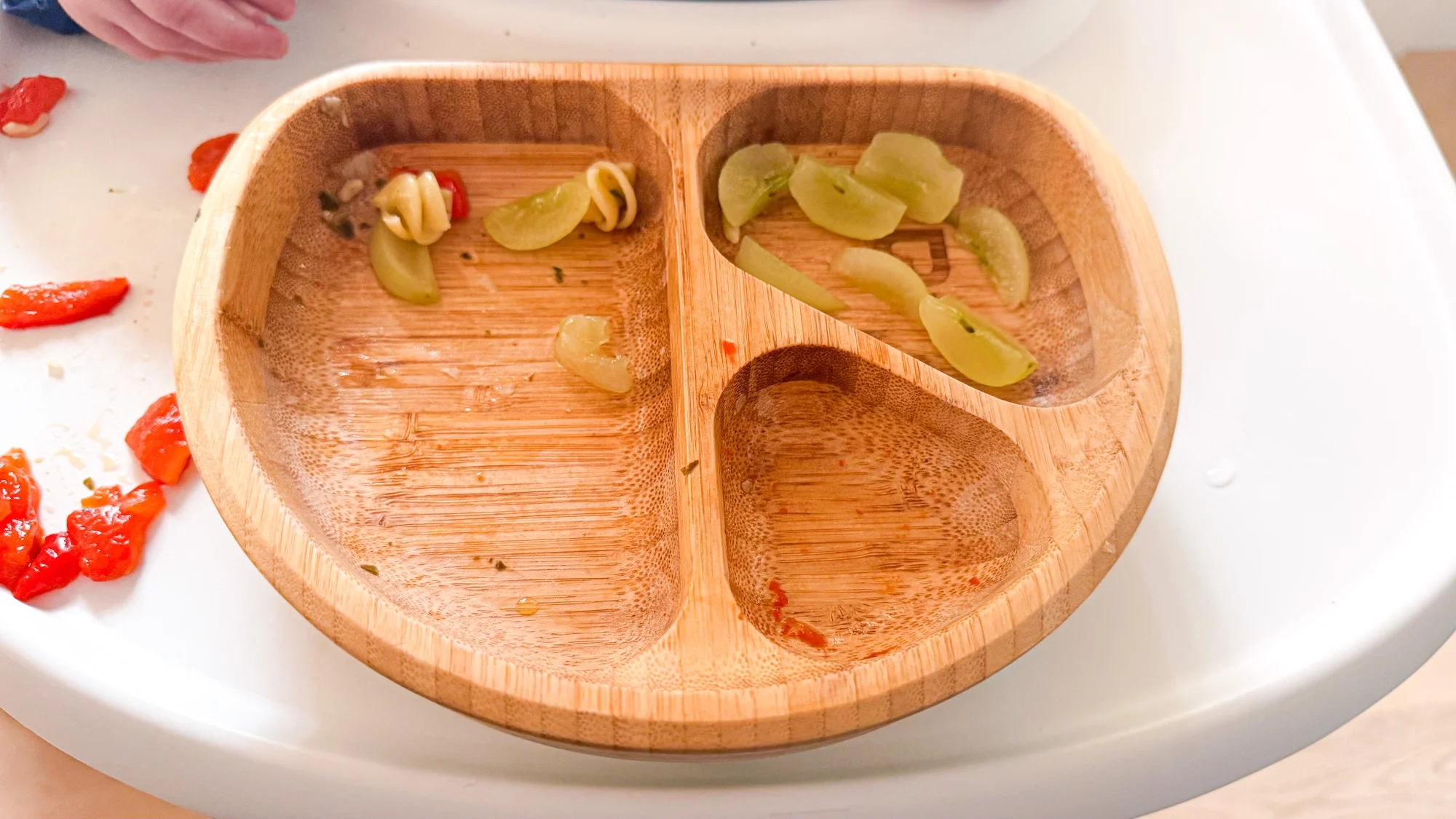 After shot of what was left of 10 month baby's meal. A few grapes, and a few red peppers in a wooden bowl.