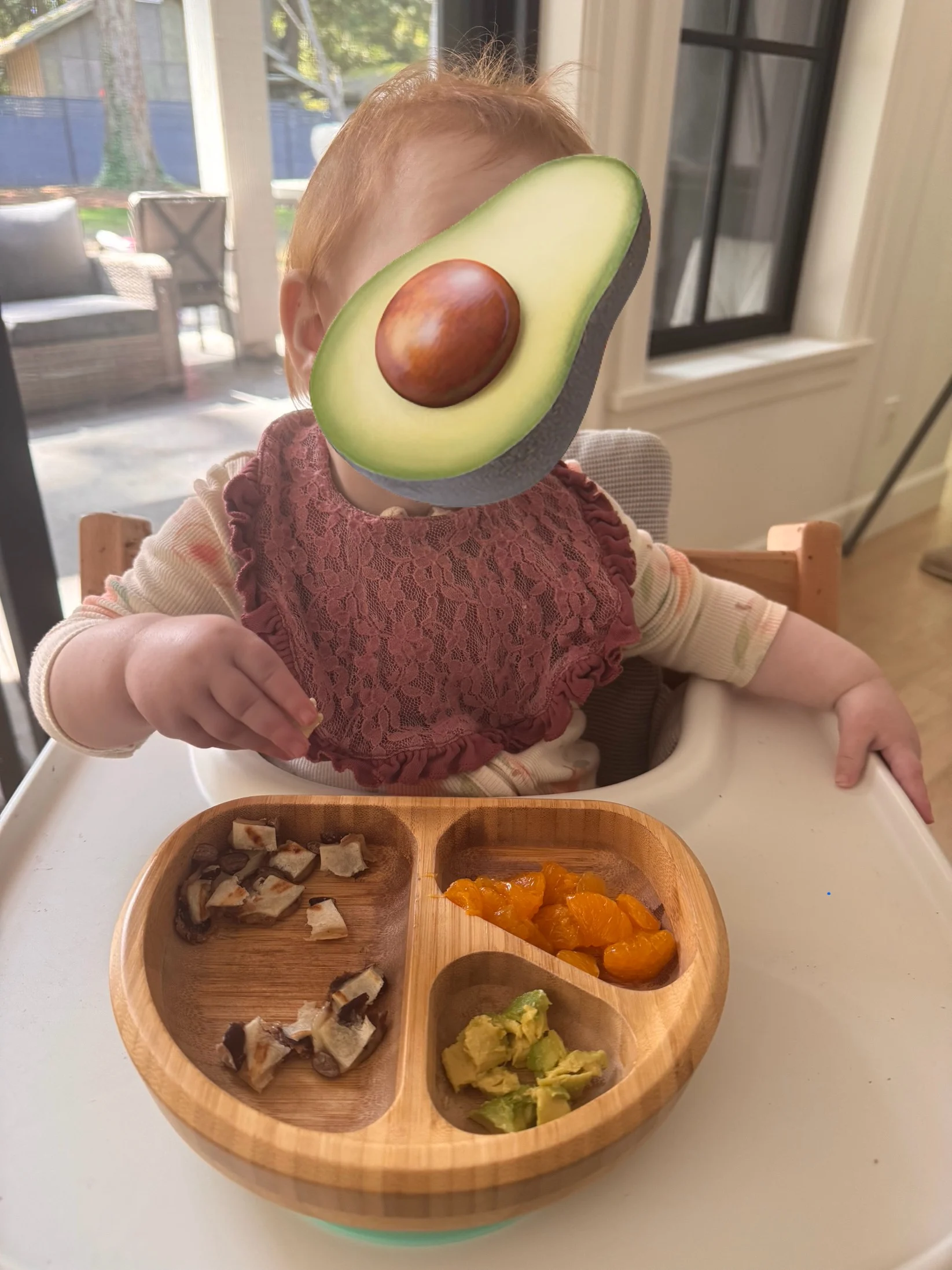 10 month baby with red hair, wearing a bib, eating a quesadilla and oranges and avocado.