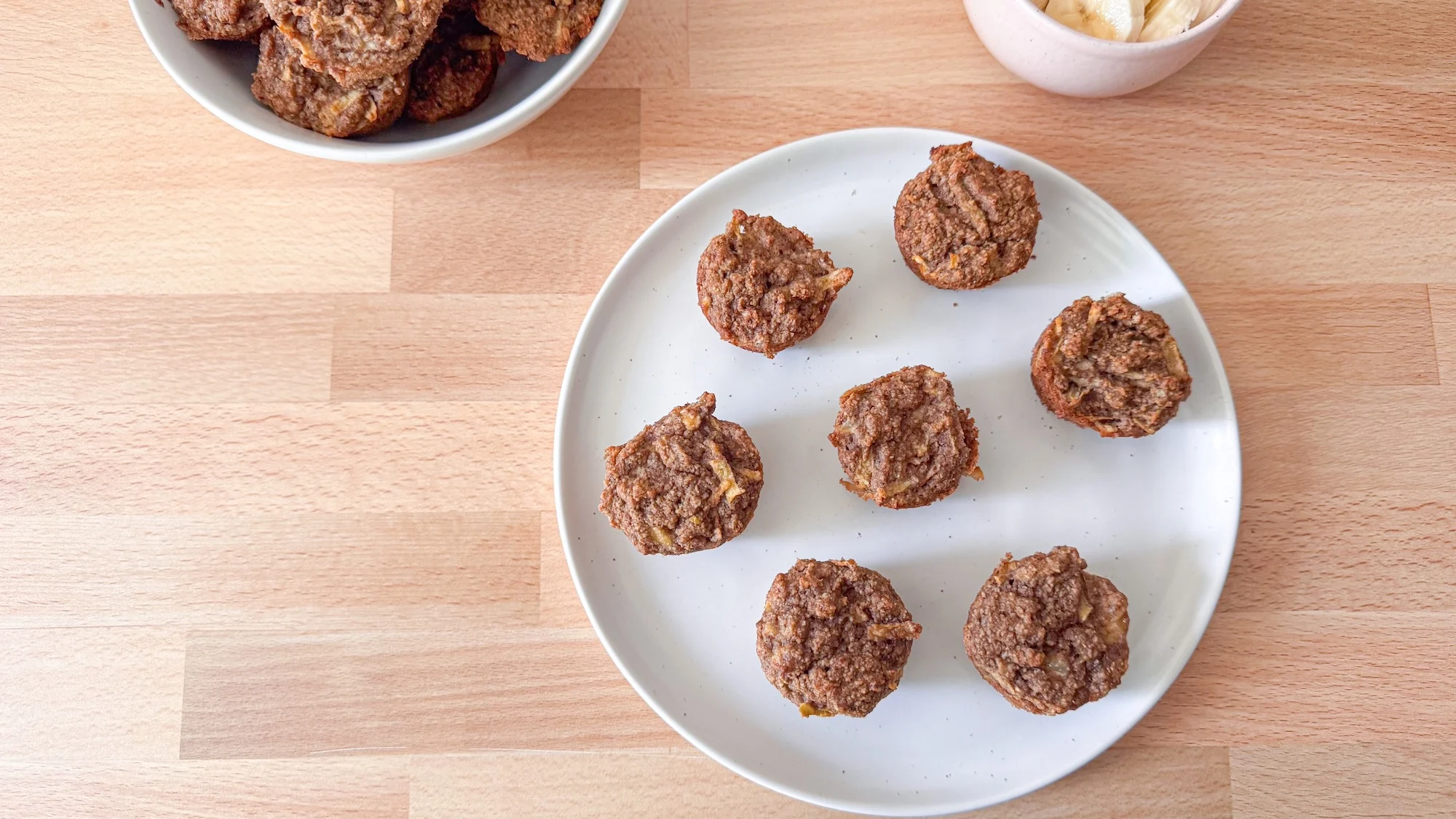 Prune muffins on white plate on wooden cutting board.