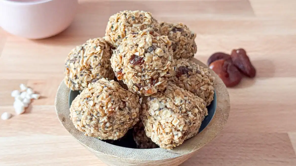Apricot and white chocolate toddler energy balls in a bowl on wooden counter with apricots and white chipits in background.