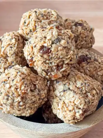 Apricot energy balls in a wooden bowl on wooden counter top.