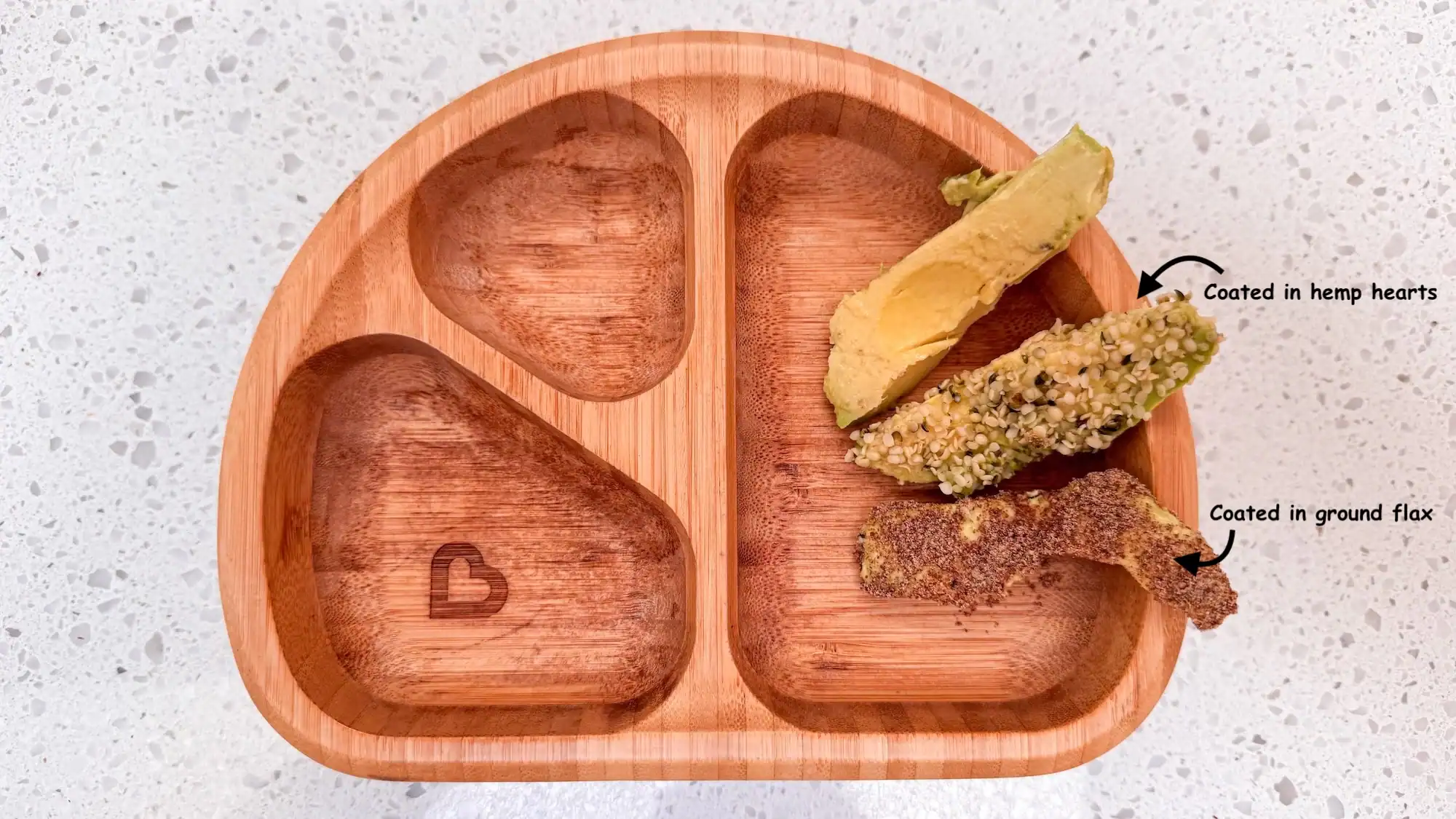 Avocado spears in a wooden baby bowl. Avocado is coated in hemp hearts and flax.
