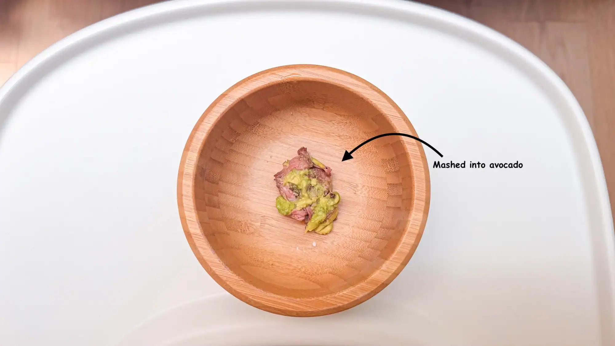 Mashed chicken in avocado in baby bowl.