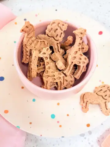 Homemade animal crackers in pink bowl on polka dot toddler plate.